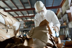 worker in protective suit sorting cardboard