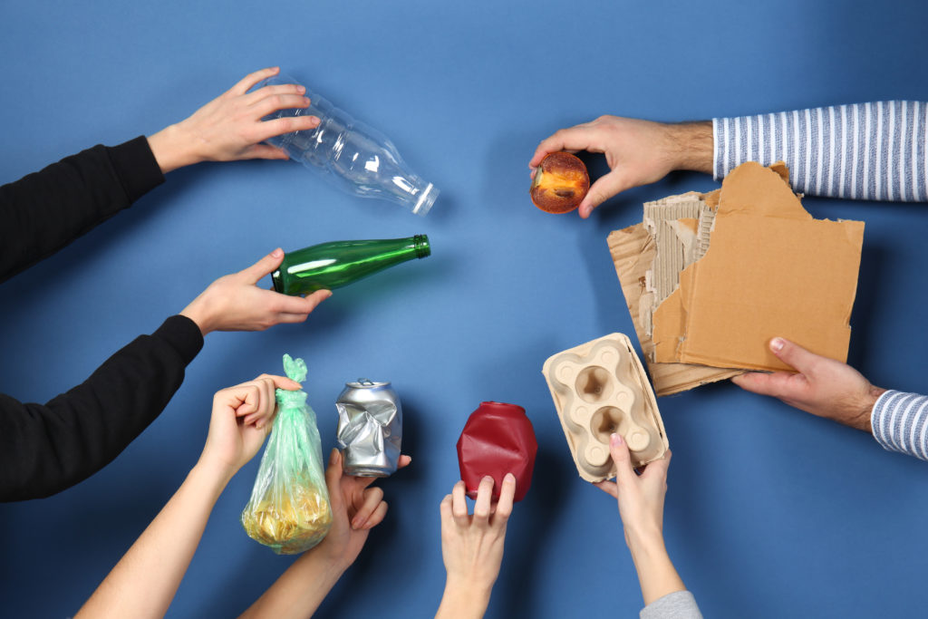 Many hands with different types of garbage on blue background