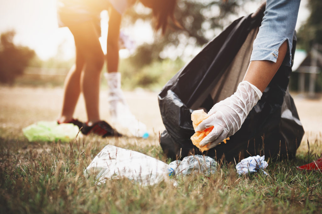 Hand picking up garbage plastic for cleaning at park