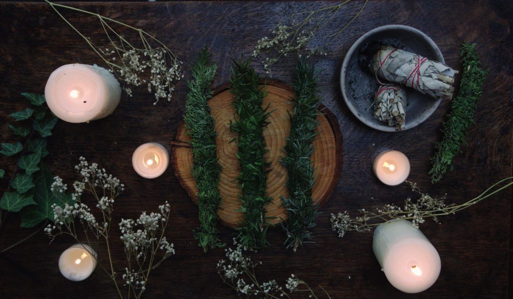 smudge sticks and candles on dark wood indicating the winter solstice