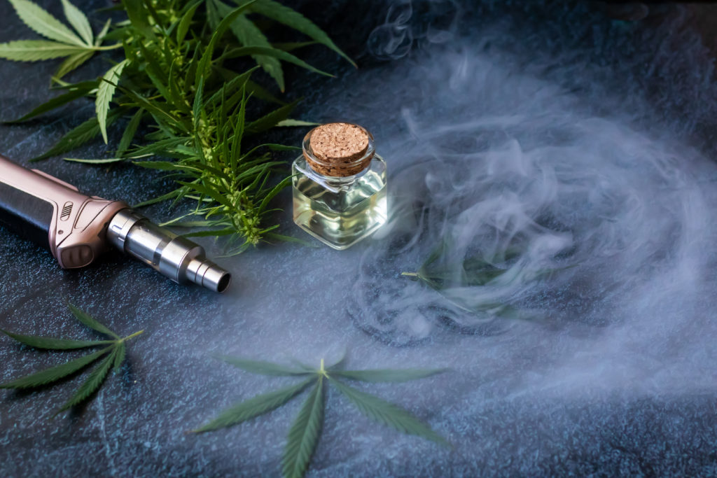 Cannabis plant, oil, and vape on dark background indicating a winter cannabis ritual